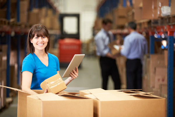 Woman in warehouse with boxes and digital tablet